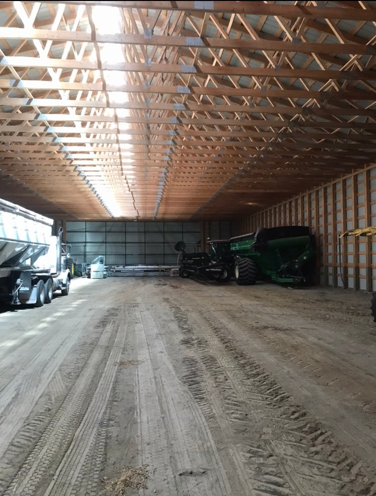 Interior of a post frame building with farm machinery in Manitoba.